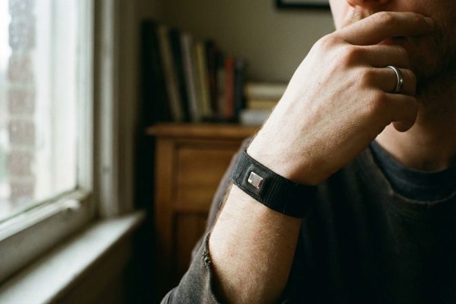Persoon draagt zwarte RFID-polsband terwijl ze nadenkend hand bij kin houdt in natuurlijk licht
