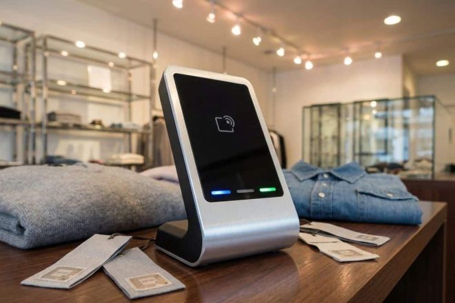 Moderne RFID-scanner op retailtoonbank met RFID-tags en kledingstukken, professionele winkelverlichting op achtergrond