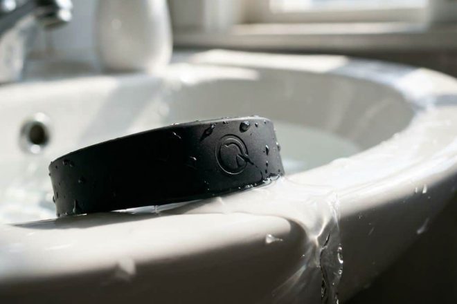 Zwarte RFID polsband met waterdruppels in witte wasbak, waterbestendig siliconen materiaal met natuurlijk licht